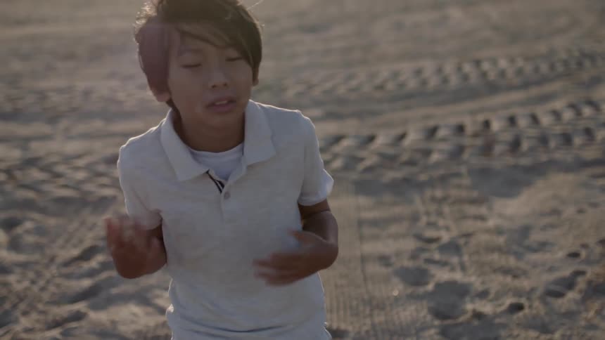 A child folds his arms on the windy beach