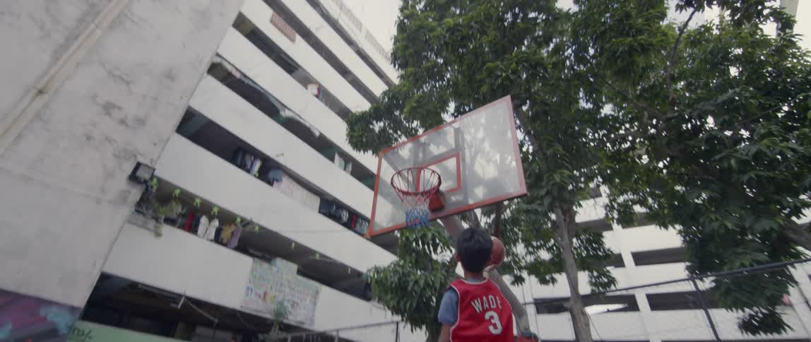 Boy plays basketball on an outdoor court
