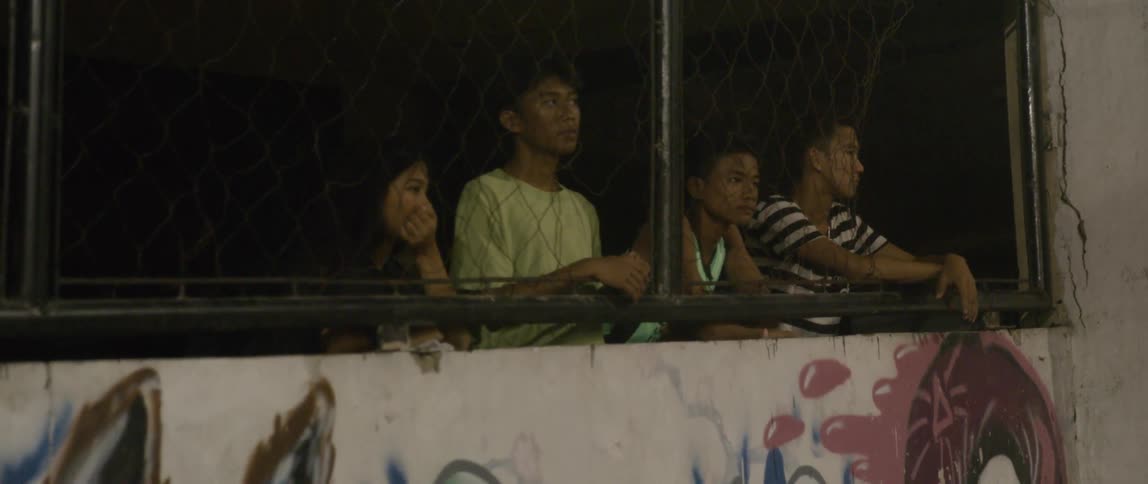 The teenagers watch on behind the fence