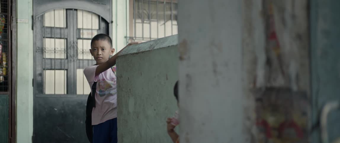 The child leans against the wall as others run by