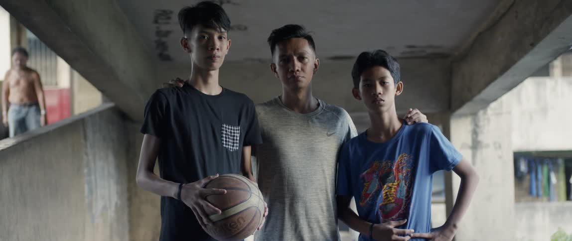 Three men stand together, and one is holding a basketball