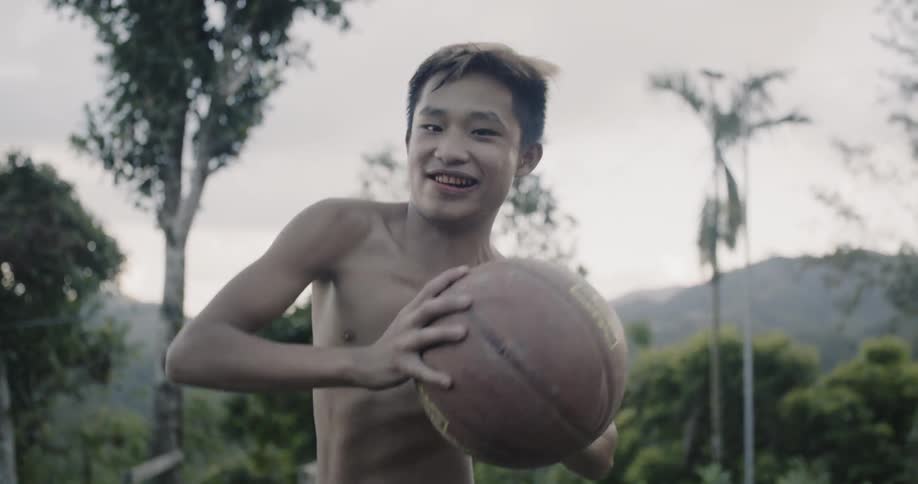 A shirtless boy dribbles a basketball