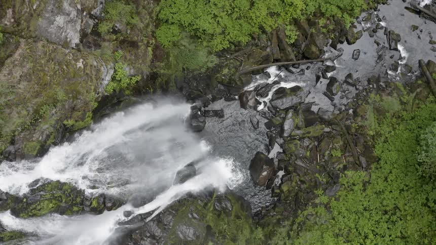 Spinning aerial shot of a cascade falling into a brook below