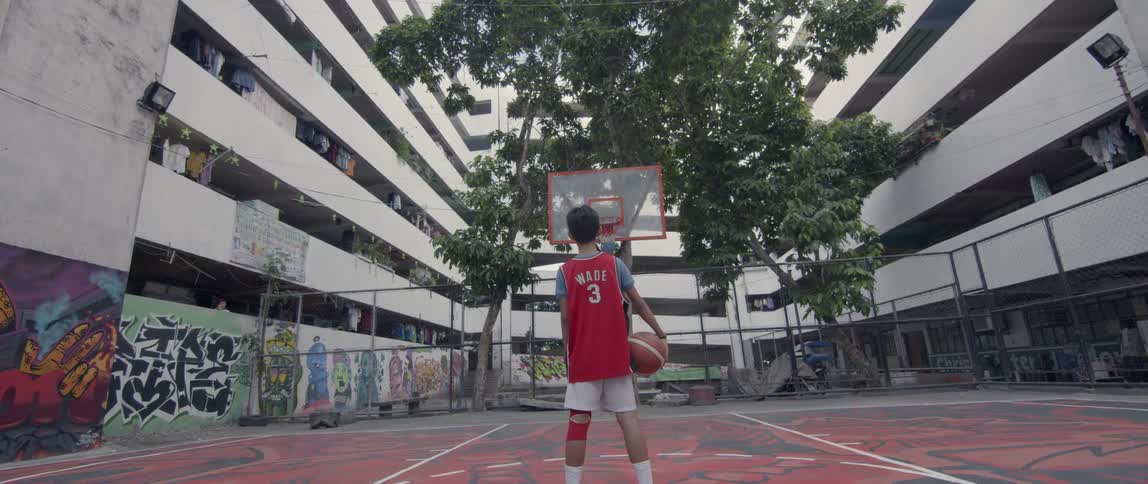 Boy stands on an outdoor basketball court