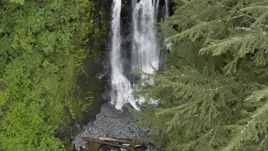 Orbiting shot of a waterfall flowing into a stream below