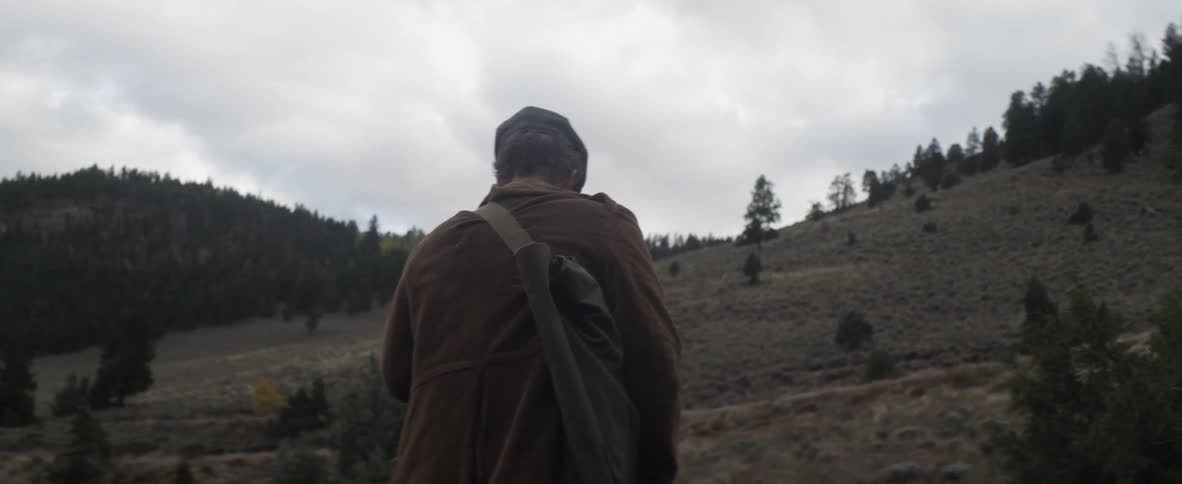 Hey man with a nap sack over his shoulder climbs a hill