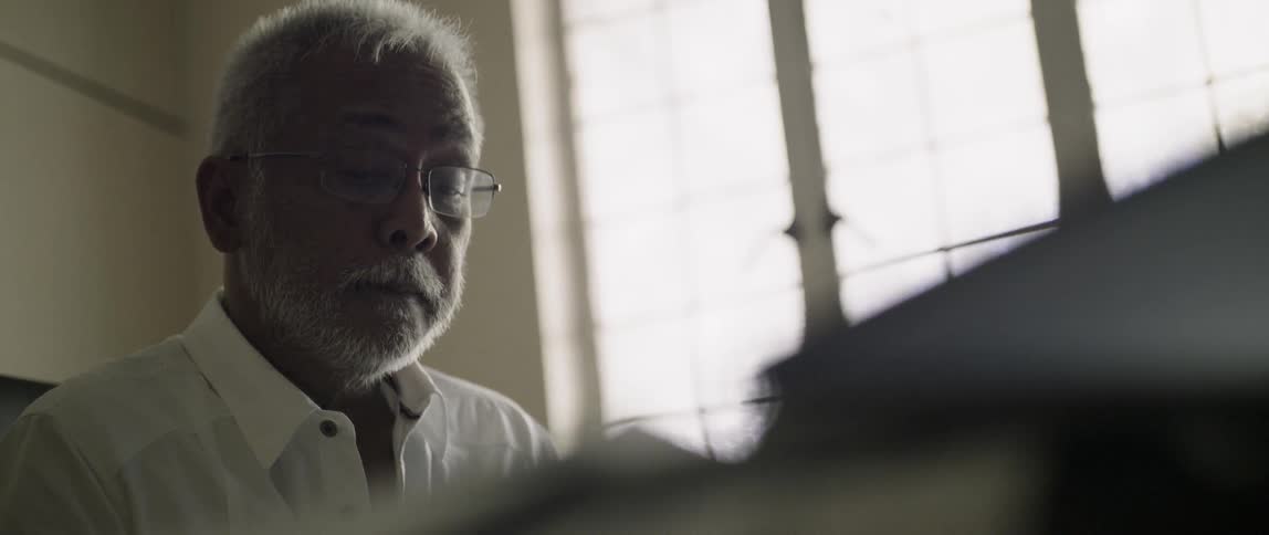 Man sits near a window looking down