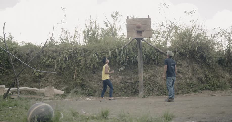 Teenagers play basketball outside on a homemade hoop