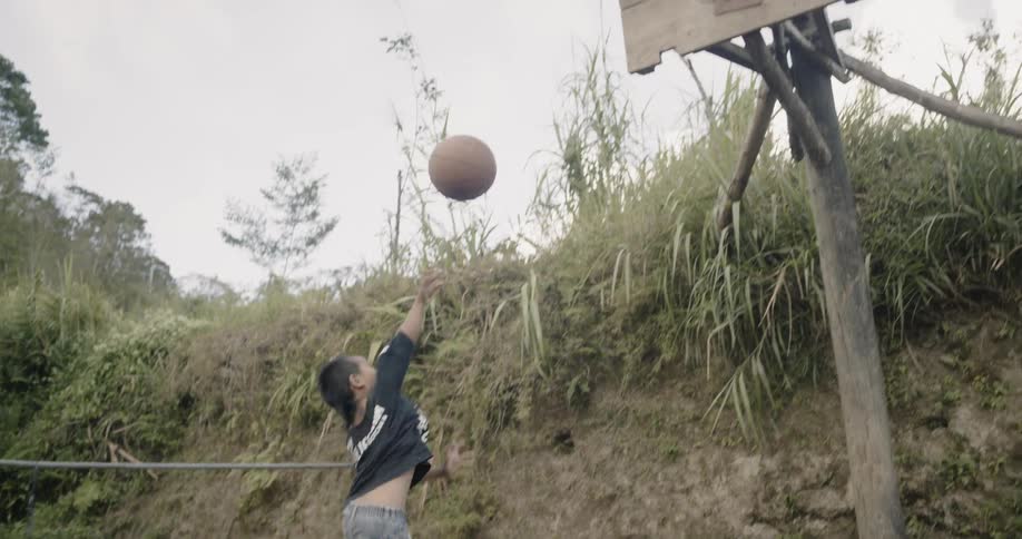 Child shoots a basketball up to a hoop and misses