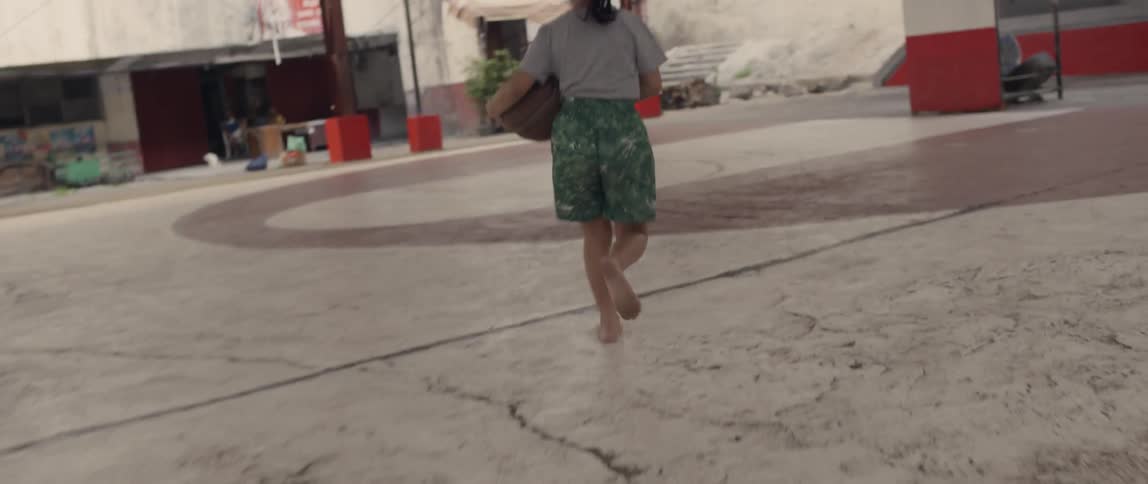 Young girl removes her flip flops then grabs a basketball and runs towards the hoop