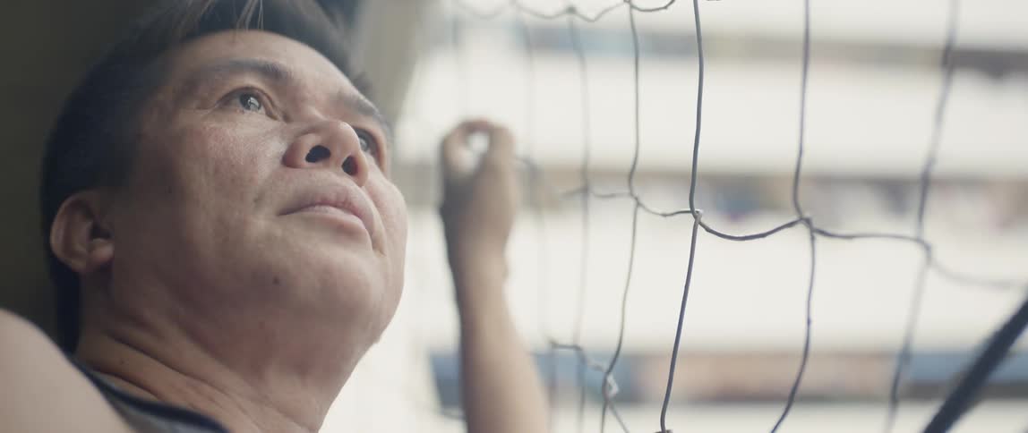 Man stands near a wire fence looking up