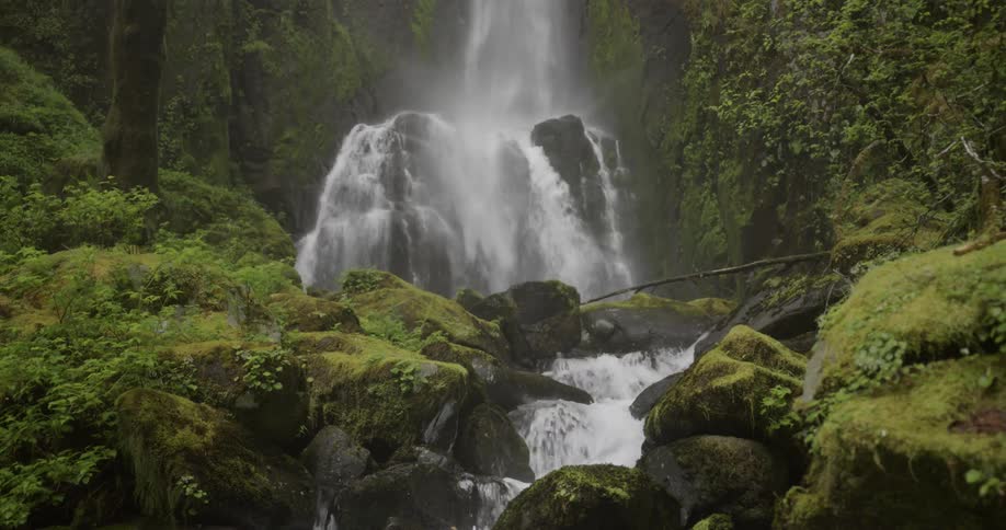 Static shot of a waterfall flowing into a stream below