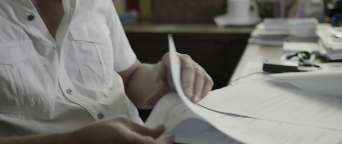 Person sits at a table looking through a pile of papers