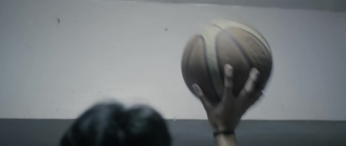 Teenager bounces a basketball against a wall