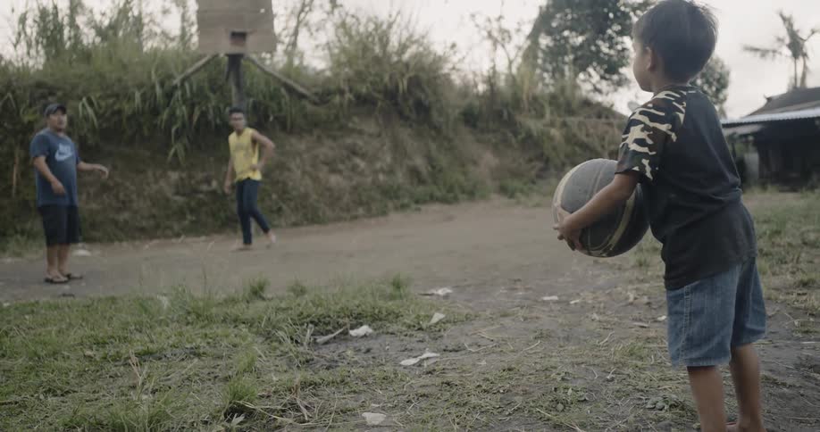 A child bounces the basketball in the dirt