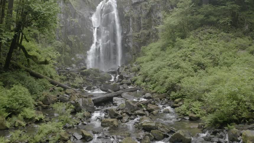 Push in shot of a cascade flowing into a rocky creek below