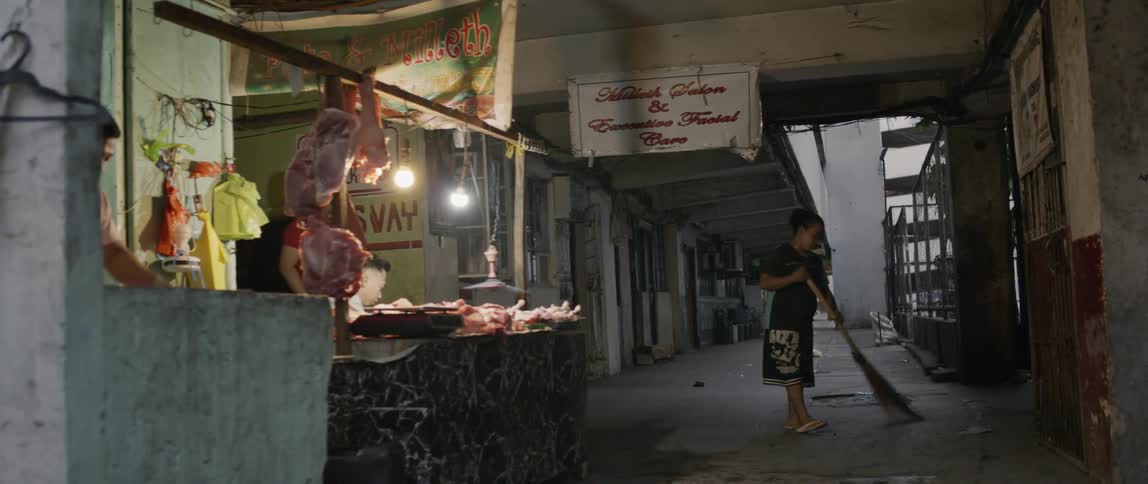 Woman sweeps the floor in a butcher shop