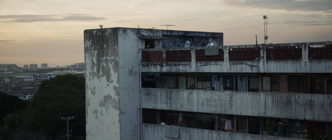 A rundown apartment complex stands in a city at sunset