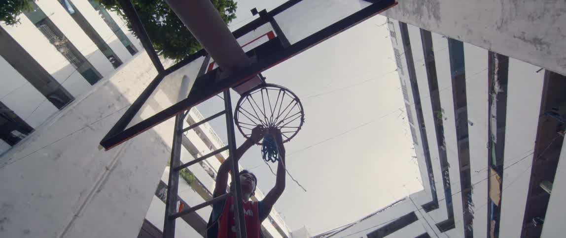 Man ties the net on a basketball hoop