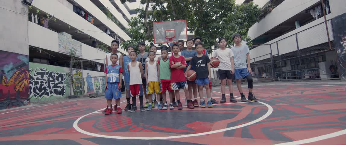 Boys stand on an outdoor basketball court
