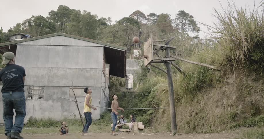 Young men shoot a basketball at an outdoor net