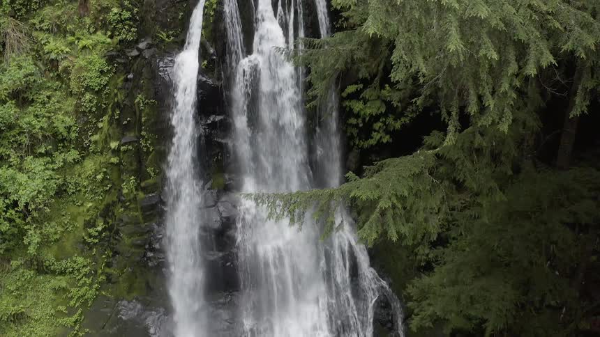 Aerial shot of a waterfall flowing over a cliff into a stream below