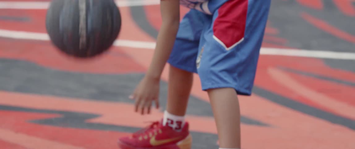 A boy dribbles a basketball on an outdoor court