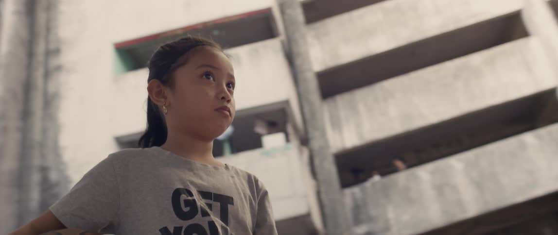 Girl holds a basketball on a court next to a tall building