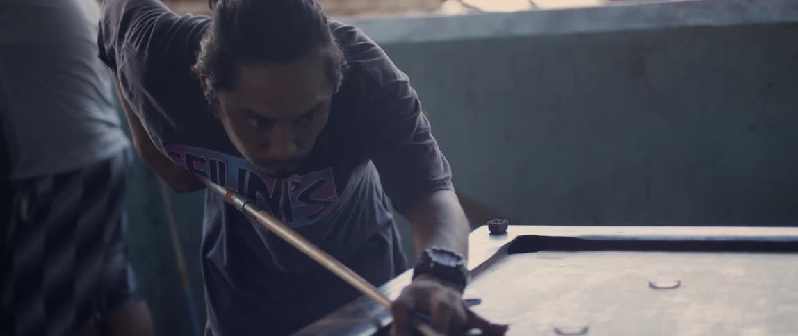 A man holds a cue stick and prepares to hit a disc on the table