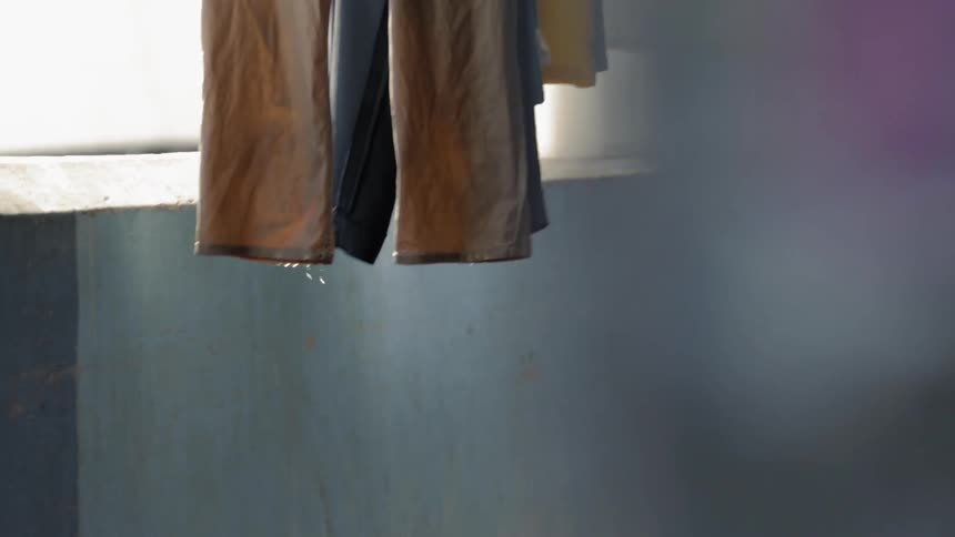 Water drips from clothing as it hangs on a balcony