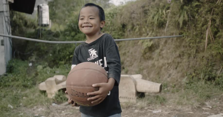 Smiling child holds a basketball outside