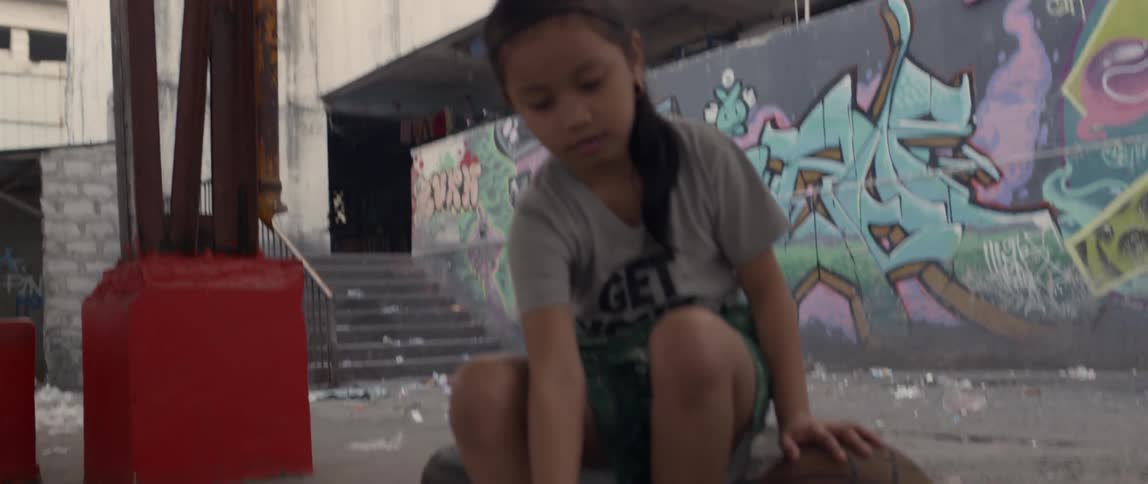 Young girl removes her flip flops then touches a basketball next to her