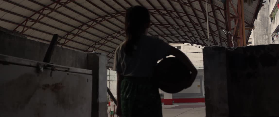 A girl carries a basketball towards a basketball court