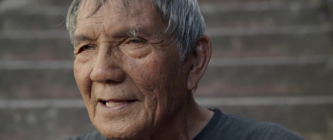 Elderly man sits on a staircase outside