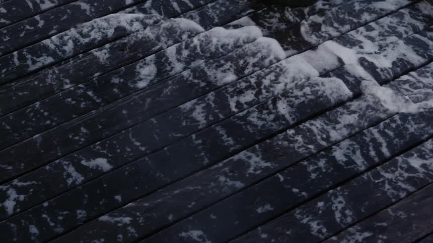 Water splashes up between the boards and rolls across the surface