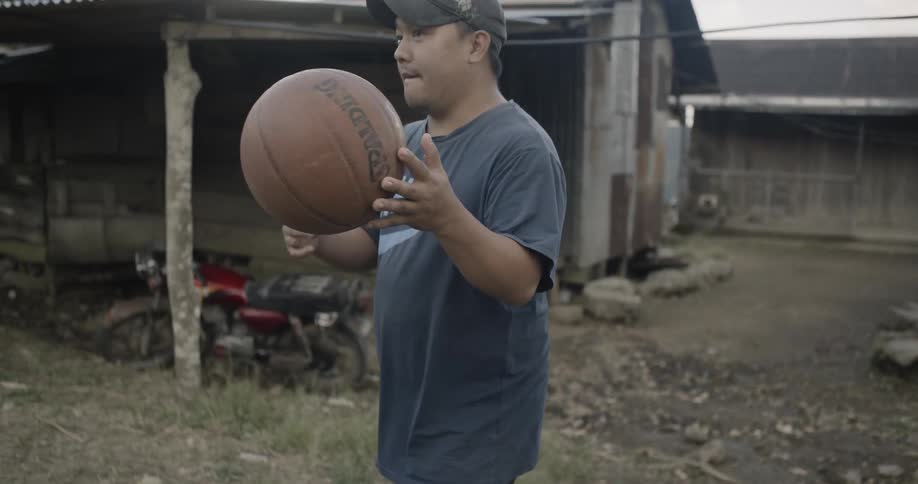 A man bounces a basketball by the hut