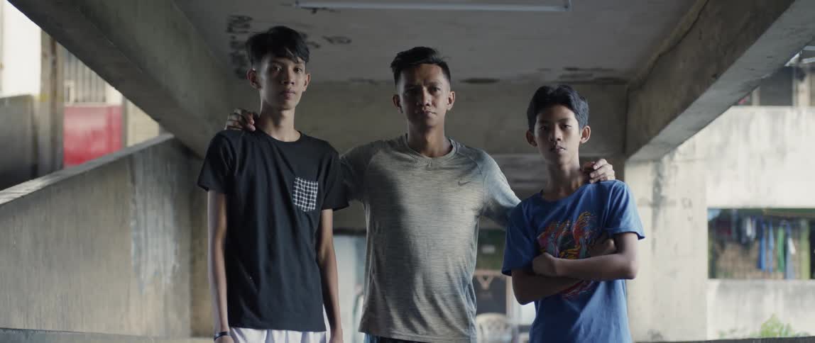 Man stands with his arms around young boys on each side of him