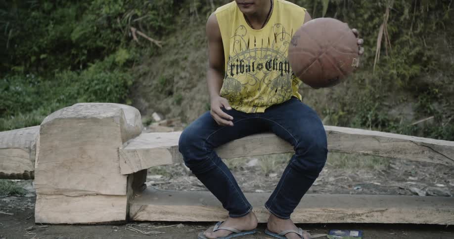 A man dribbles his basketball sitting down