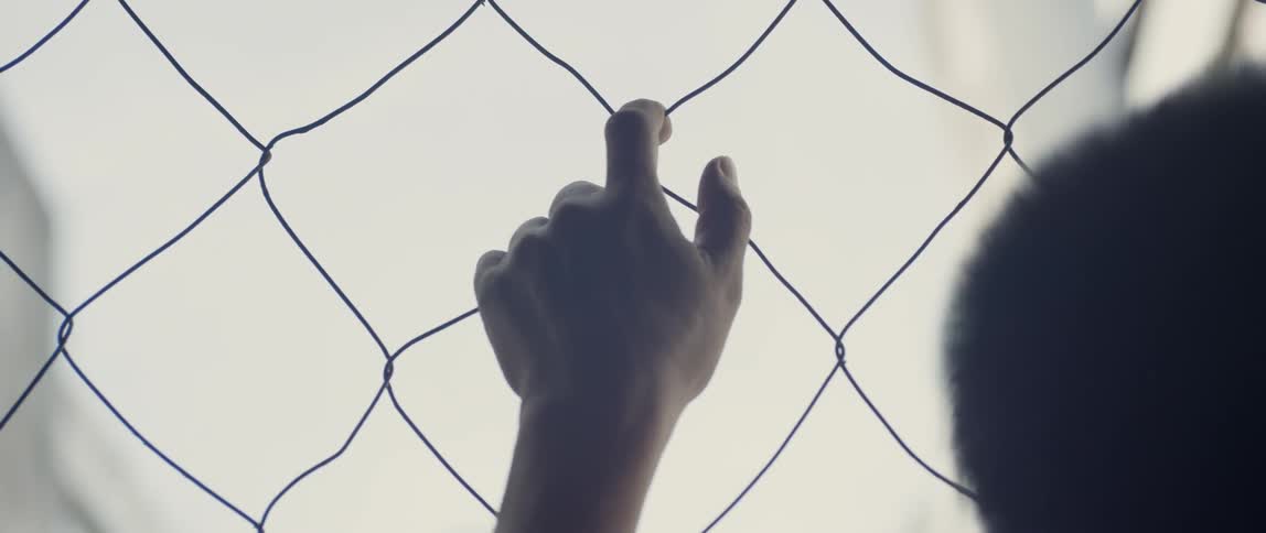 A person hangs on the chain link fence