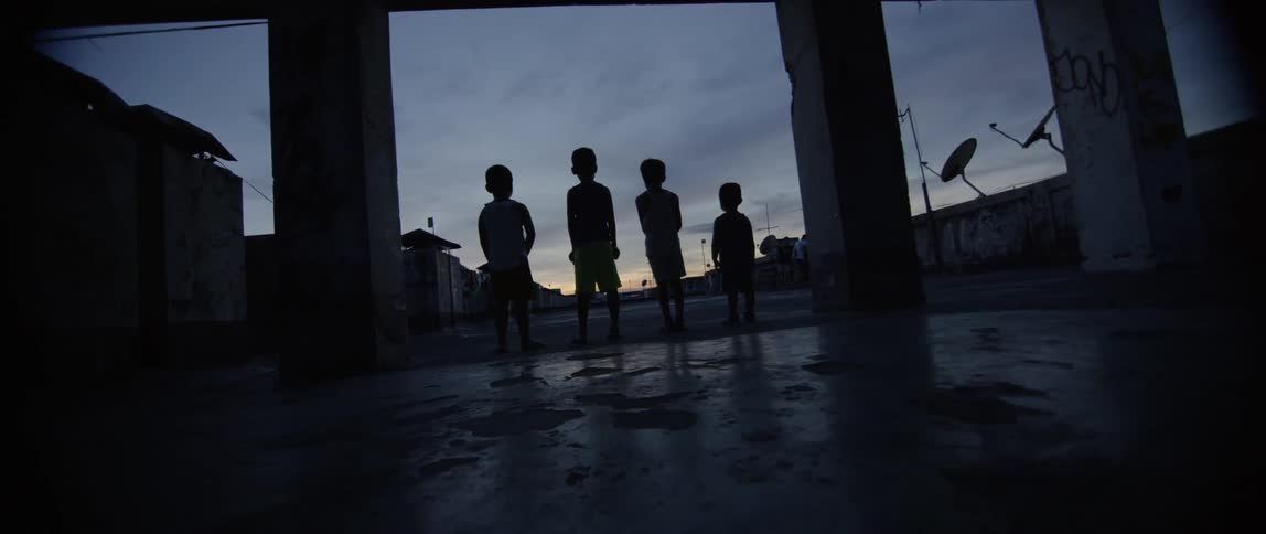 Several children stand outside at sunset