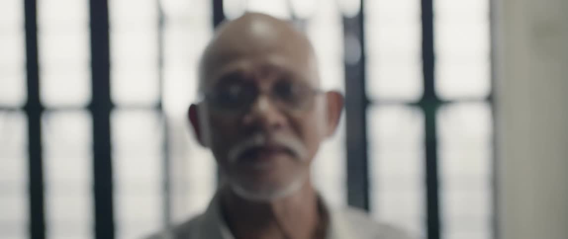 Elderly man stands in front of a window