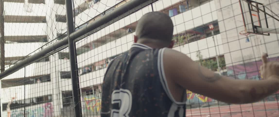 A man walks up to a fence and leans against it as he looks through