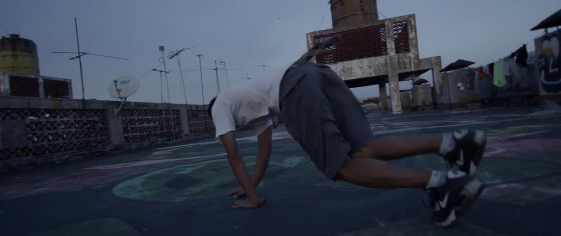 A boy break dances on a rooftop