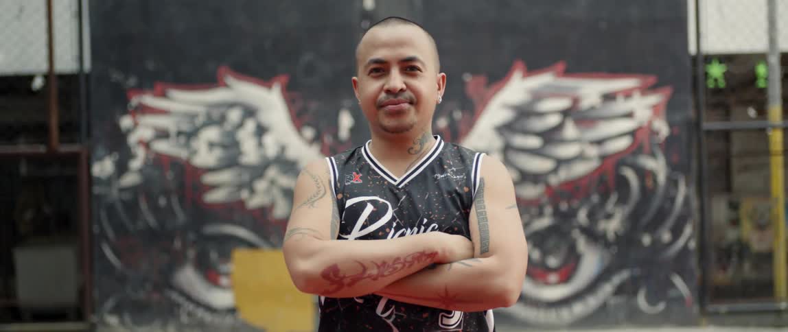Man with tattoos stands with his arms crossed in front of his chest