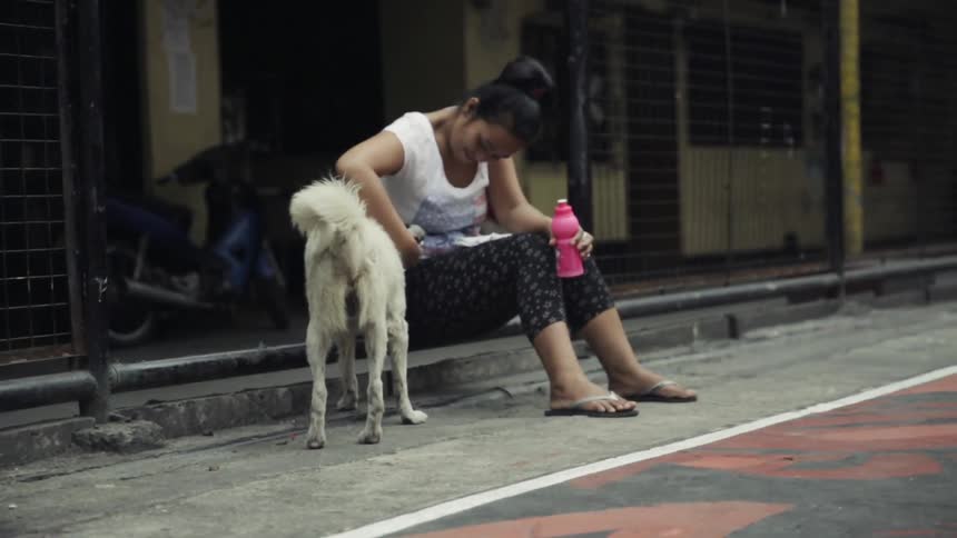 A woman sits near the fence with a dog