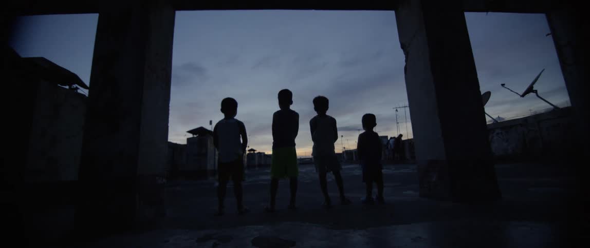 Young boys stand outside at dusk