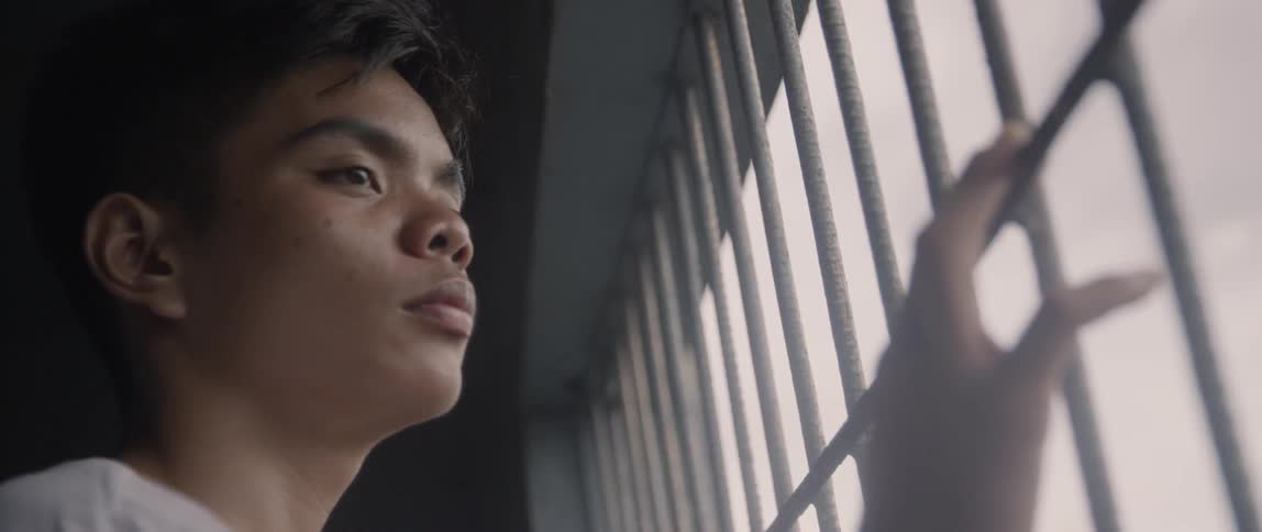 Teenager looks through a metal gate