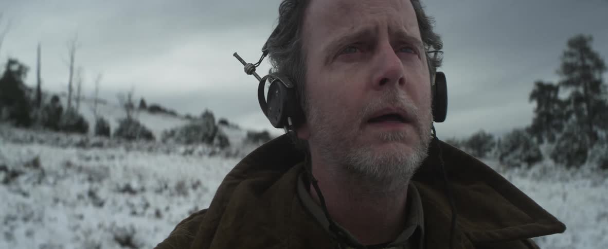 A man with headphones standing in a snowy field