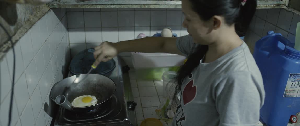 Woman fries an egg at home