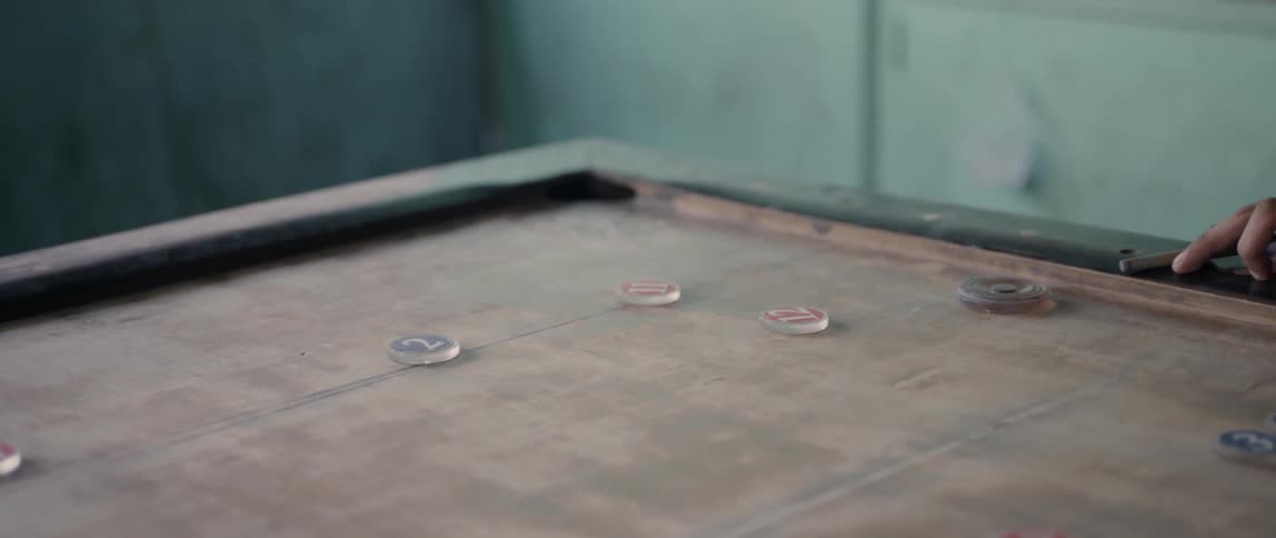 Person shoots a disc on a table at smaller discs